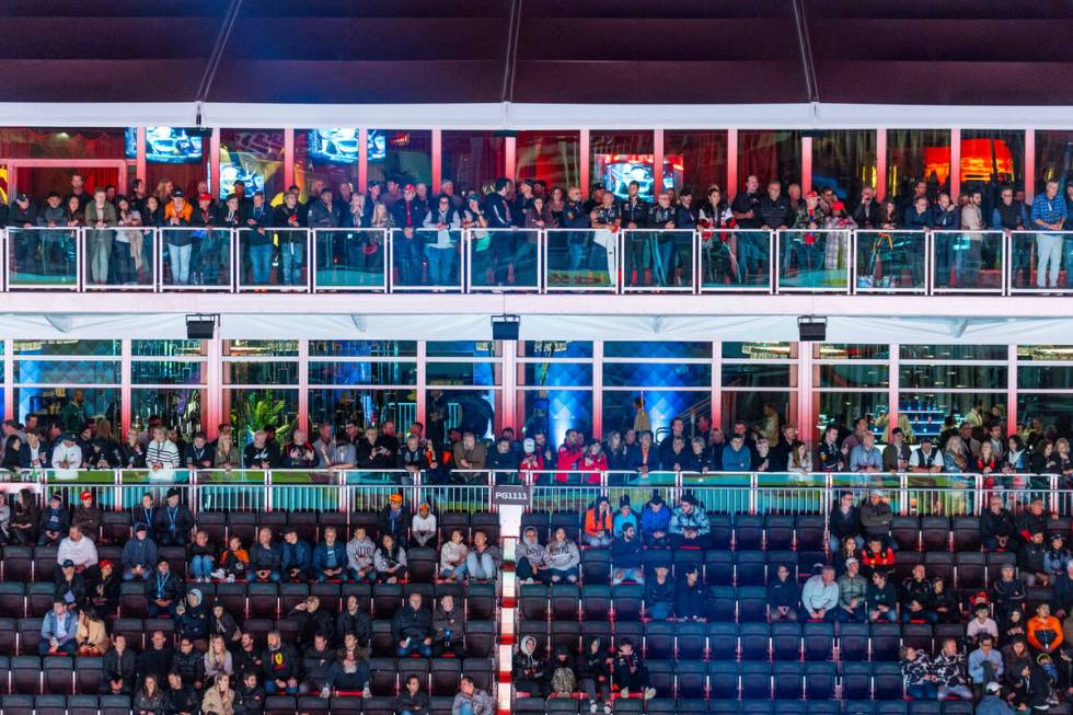 Fans sit and stand to watch during the qualifying session on the second night of the Las Vegas ...