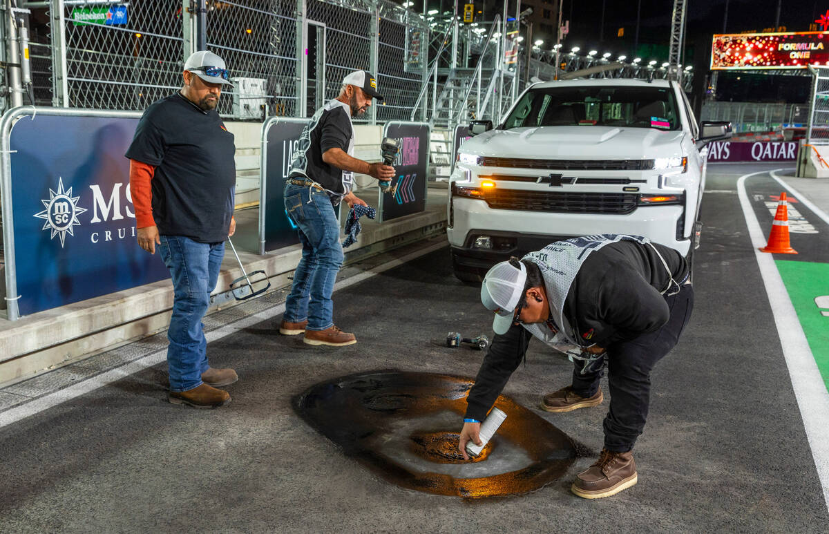 A crew from Las Vegas Paving ensures that a valve cover is secure and the pavement around it is ...