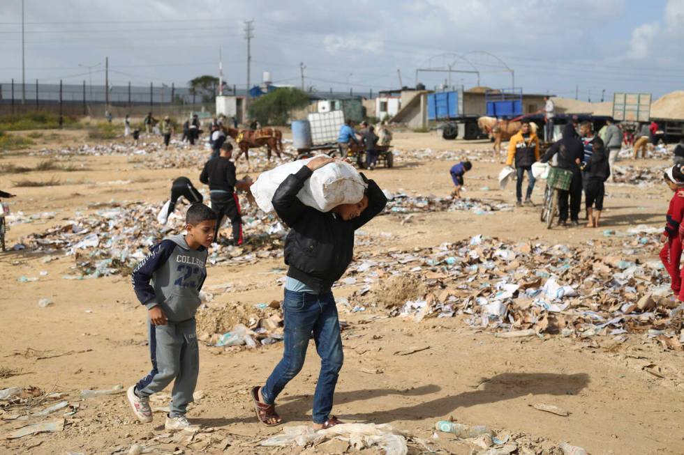 A Palestinian boy carries water looted from the humanitarian aid trucks during the ongoing Isra ...