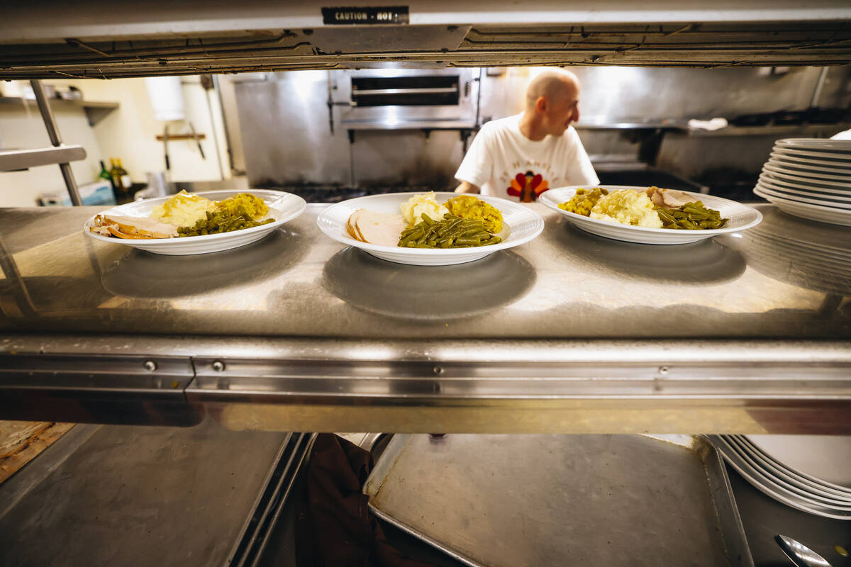 Plates of thanksgiving food sit-in the kitchen ready to be given to families at Piero’s ...