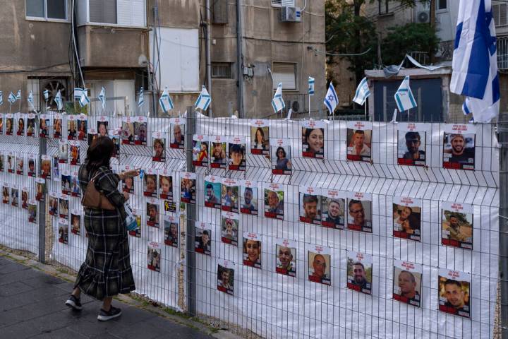 A woman looks at photographs of hostages, mostly Israeli civilians who were abducted during the ...