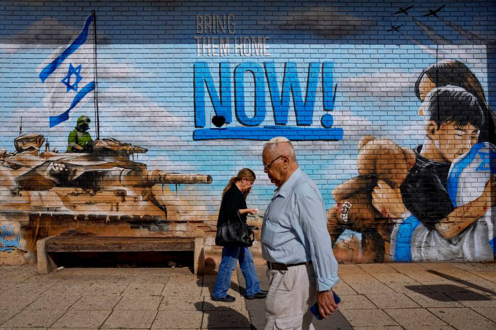 People walk past graffiti calling for the return of the hostages kidnapped during the Oct. 7 Ha ...