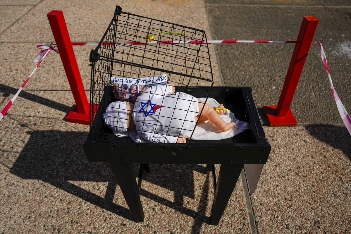 An installation of a baby and a pillow with the Hebrew writing "These are all our children ...