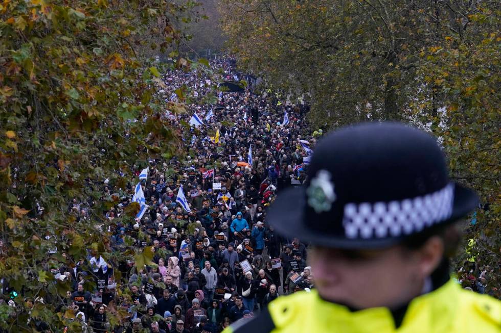 A policewoman stand guard on a bridge as an anti-Semitism demonstration with protesters holding ...