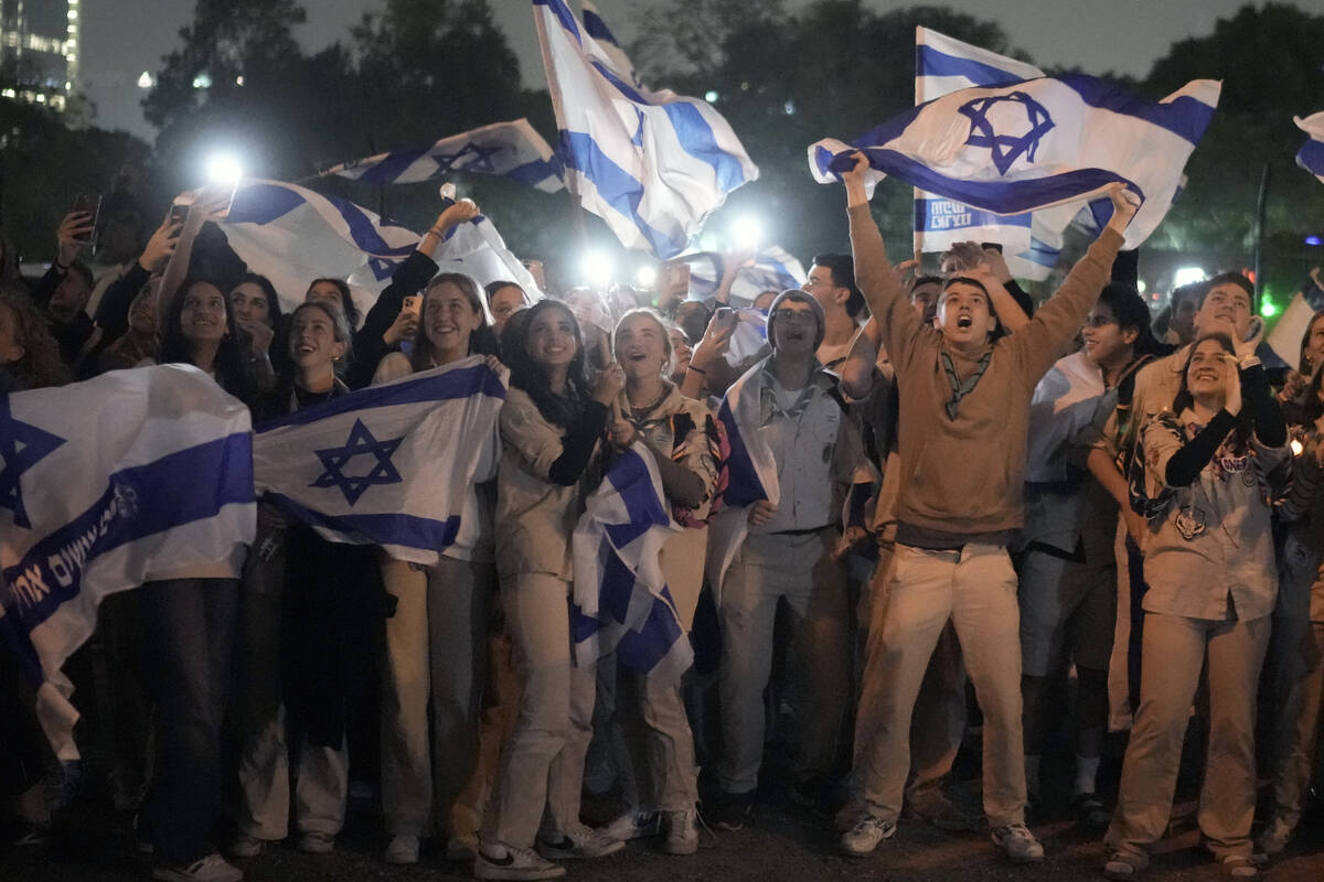 A group of Israelis celebrate as a helicopter carrying hostages released from the Gaza Strip la ...