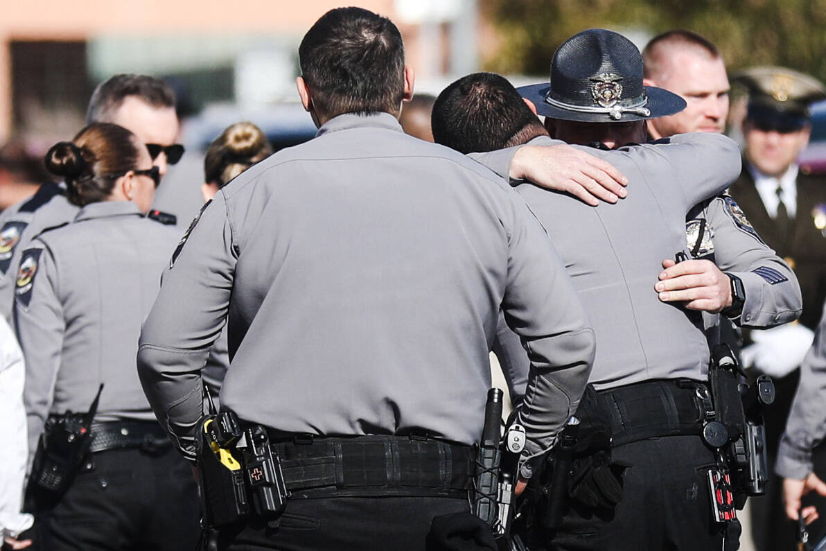 Police embrace each other after the procession for a slain Nevada Highway Patrol trooper outsid ...