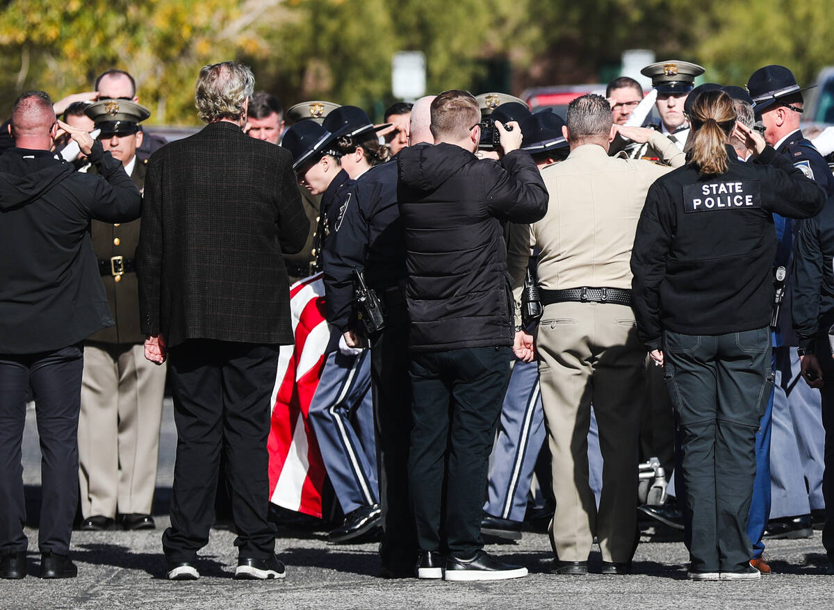 Police salute as the body of a slain Nevada Highway Patrol trooper is led into the coroner’s ...