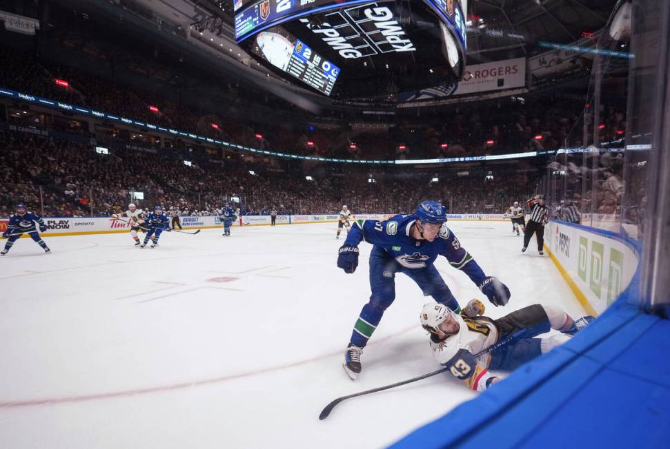 Vancouver Canucks' Tyler Myers (57) checks Vegas Golden Knights' Paul Cotter (43) into the boar ...