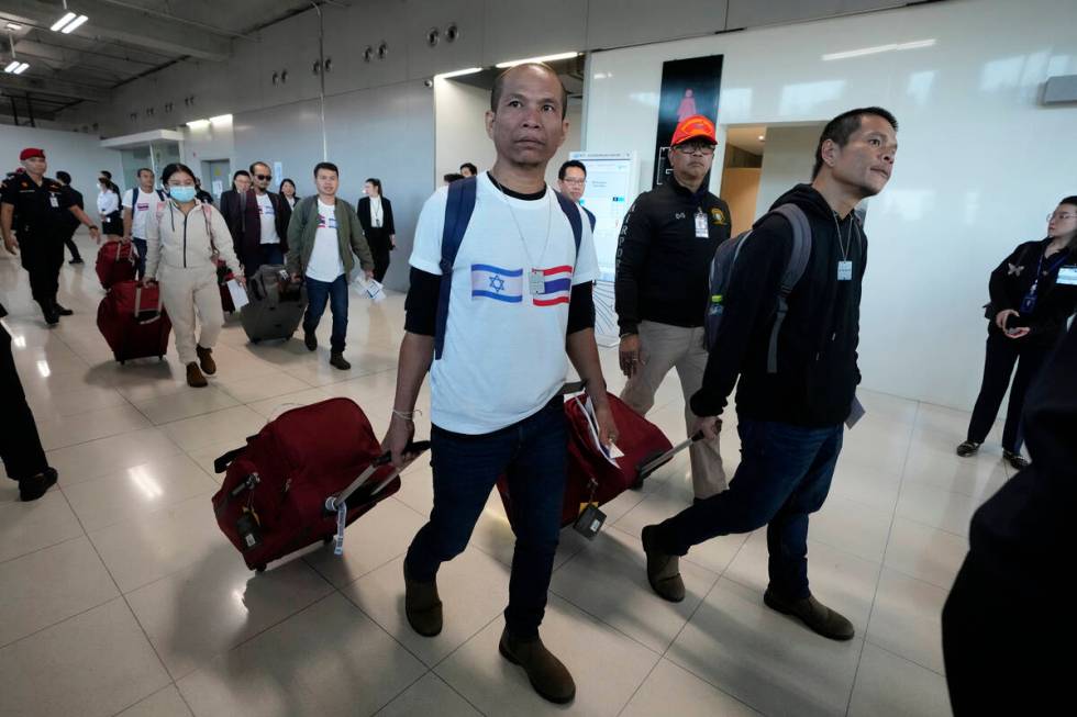 A Thai man wearing a shirt with the Israeli flag, left, and a Thai flag arrives at Suvarnabhumi ...