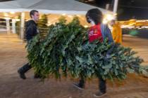 Gabriel Bennett, left, and Dylan Zaudke carry a customer's tree to their vehicle at Rudolph's C ...