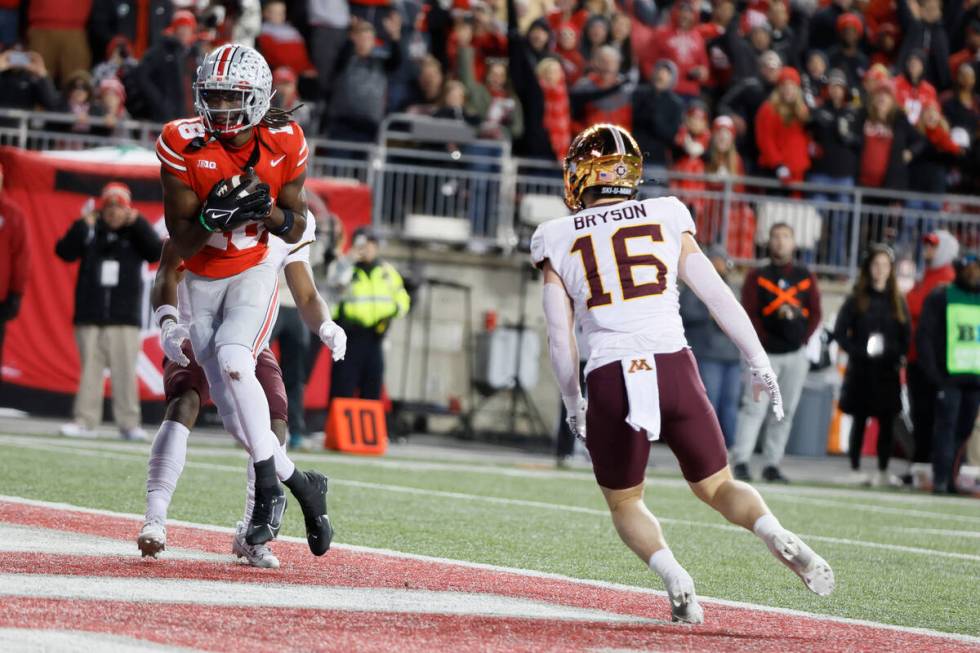 Ohio State receiver Marvin Harrison, left, scores a touchdown as Minnesota defensive back Colem ...