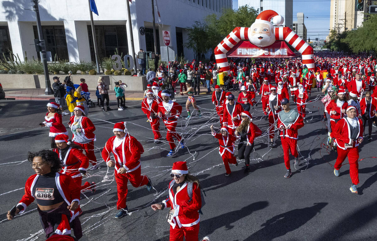 Participants in the 1-mile jaunt leave the starting line during the Las Vegas Great Santa Run t ...