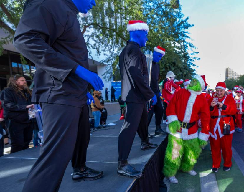 A grinch looks to the Blue Man Group at the starting line during the Las Vegas Great Santa Run ...