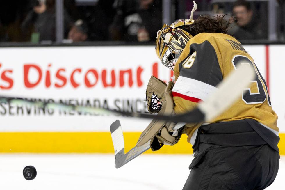 Golden Knights goaltender Logan Thompson (36) loses his helmet while saving the puck during the ...