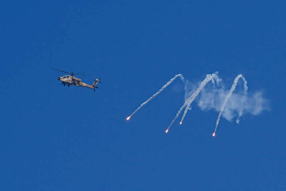 An Israeli military helicopter releases flares over the Israel-Gaza border as seen from souther ...