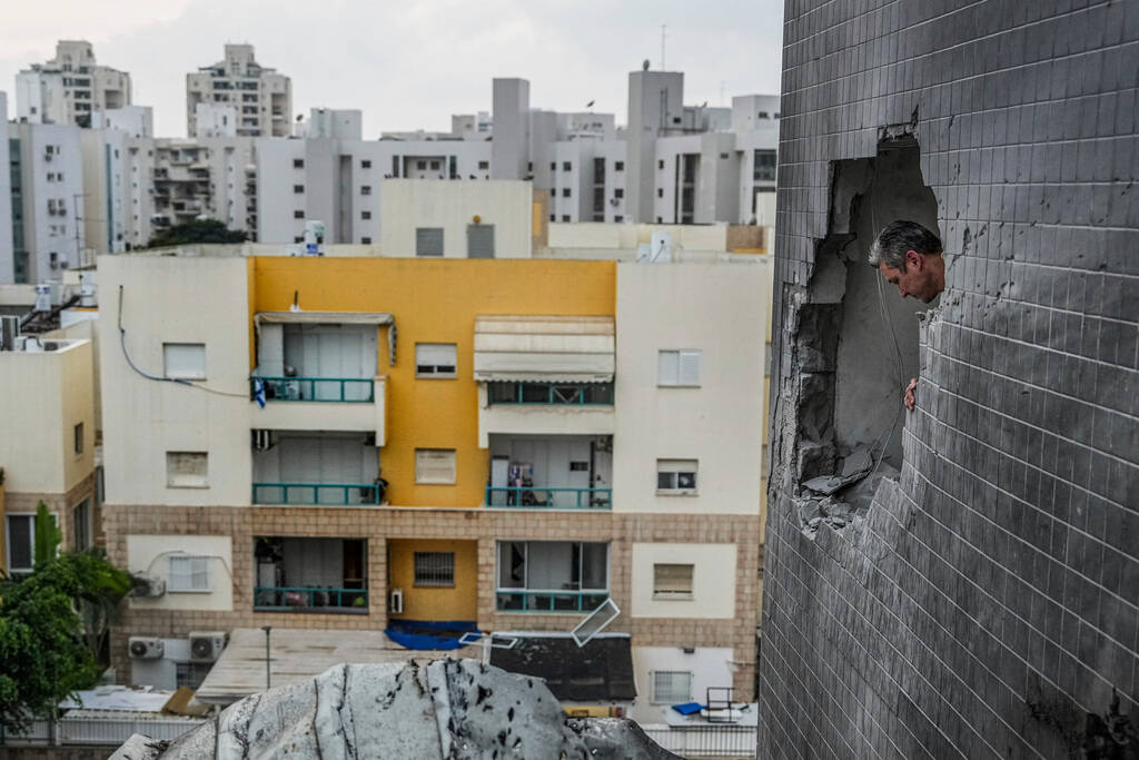 A man looks through a hole in the wall of a house as a result of rockets fired from the Gaza St ...