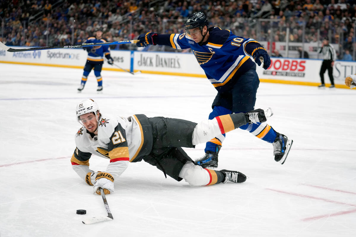 Vegas Golden Knights' Brett Howden (21) reaches for a loose puck as St. Louis Blues' Brayden Sc ...