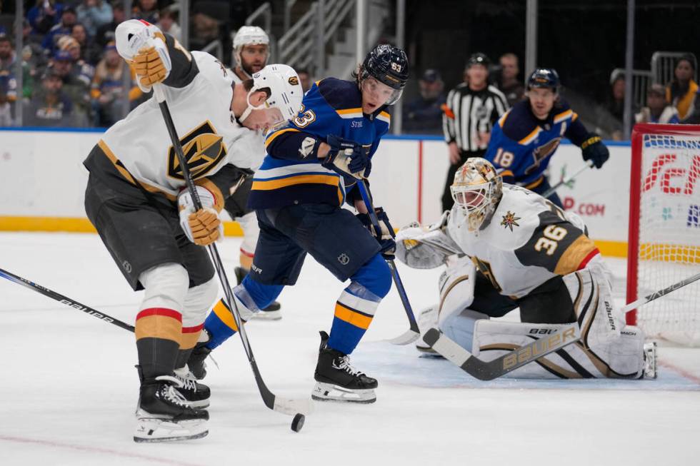 Vegas Golden Knights' Ben Hutton, left, handles the puck as Golden Knights goaltender Logan Tho ...