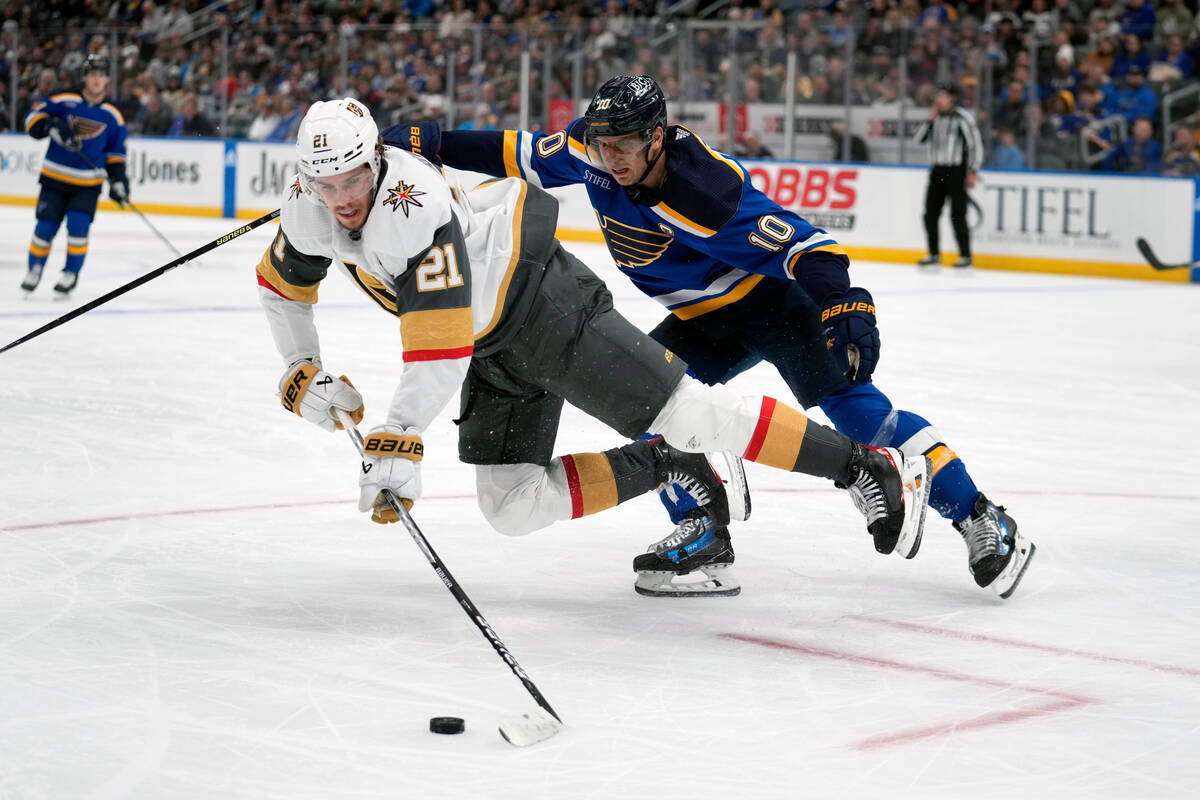 Vegas Golden Knights' Brett Howden (21) reaches for a loose puck as St. Louis Blues' Brayden Sc ...