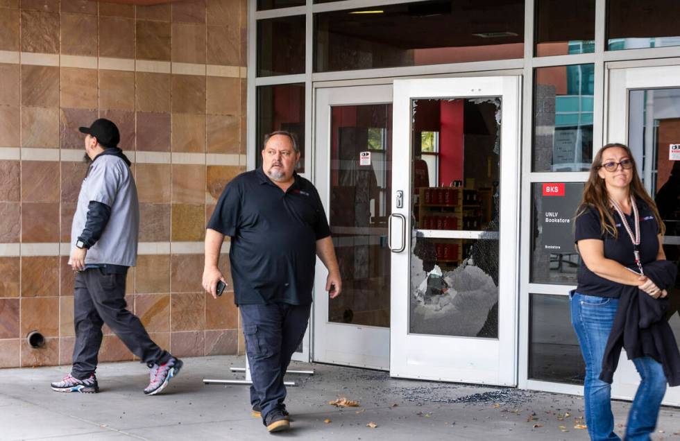 Personnel walk from the UNLV Bookstore with shattered front door glass following the shooting y ...