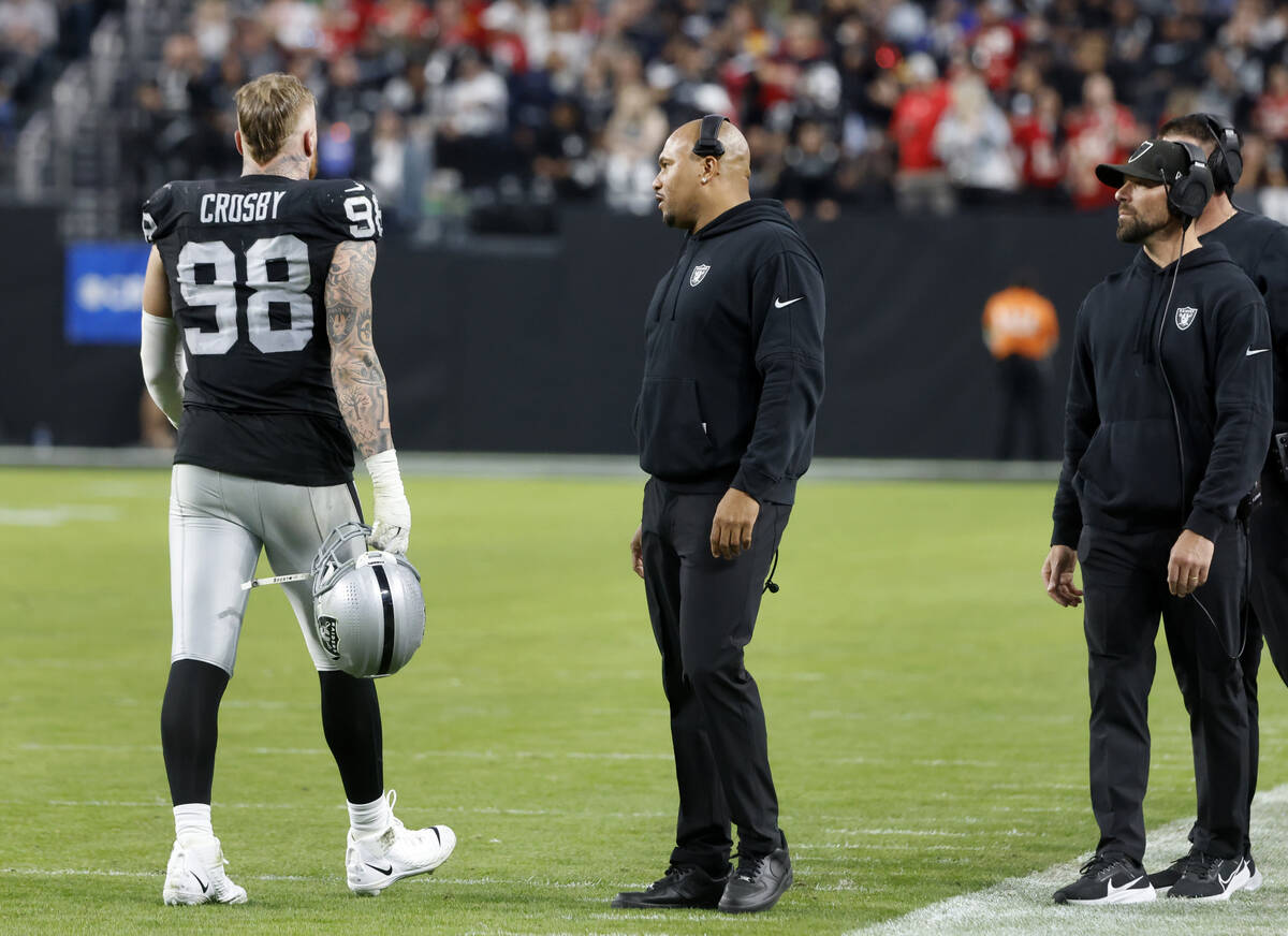 Raiders Interim Coach Antonio Pierce, center, talks to Raiders defensive end Maxx Crosby (98) a ...