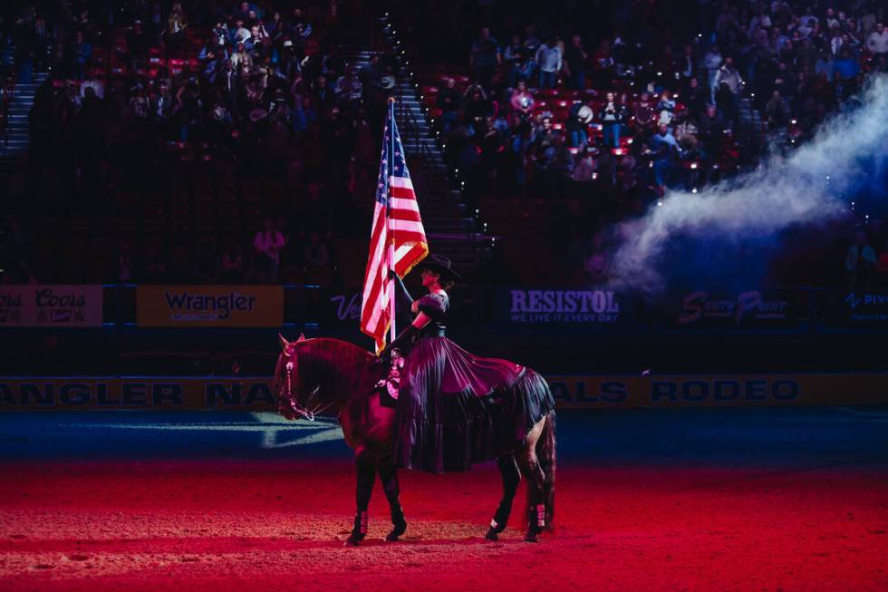 A cowgirl holds the American flag during the national anthem at the National Finals Rodeo openi ...