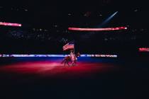 A woman rides a horse during the national anthem during day three of the National Finals Rodeo ...