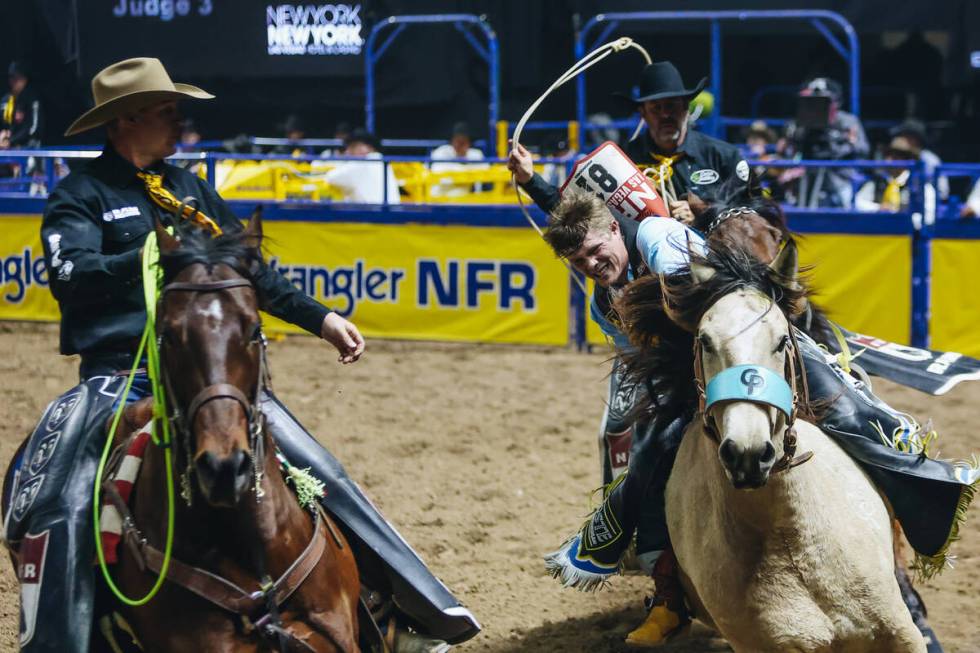 Jacob Lees gets help from the pick up men during bareback riding on day three of the National F ...