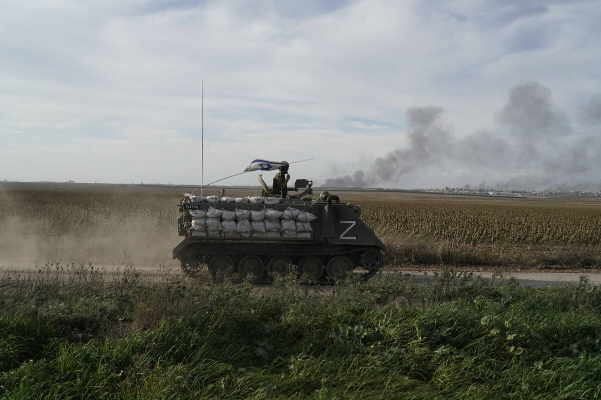 Israeli soldiers patrol as the smoke rises from the Gaza Strip after Israeli strikes on Saturda ...