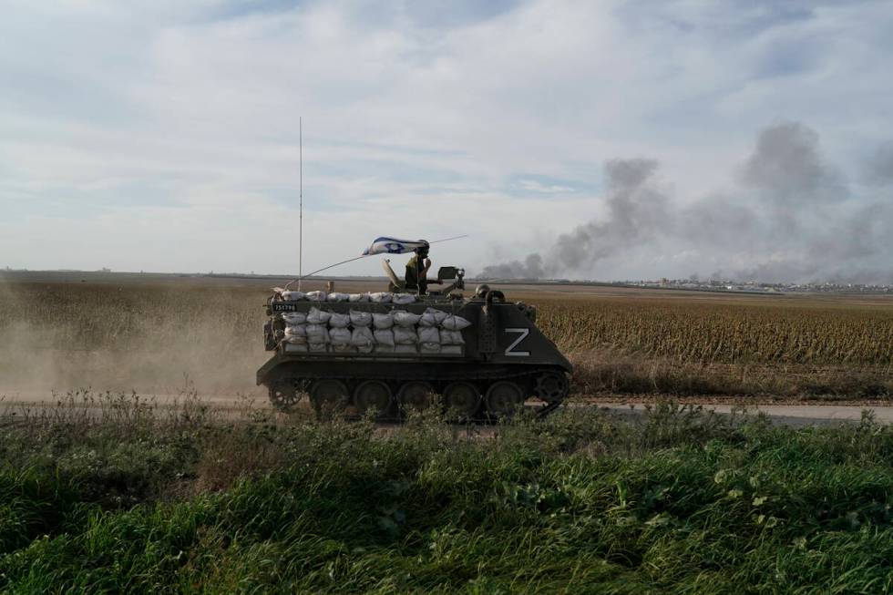 Israeli soldiers patrol as the smoke rises from the Gaza Strip after Israeli strikes on Saturda ...