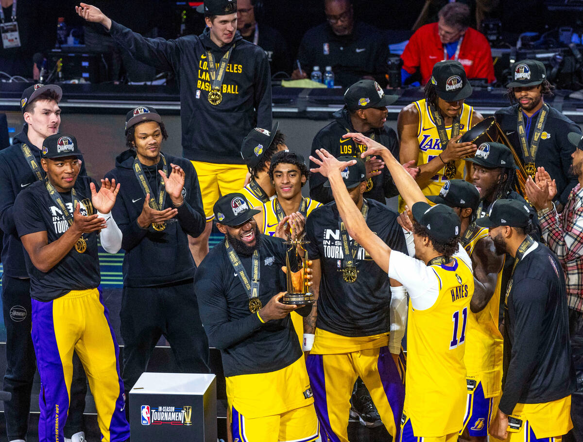 Los Angeles Lakers forward LeBron James (23) holds up his MVP trophy about teammates after defe ...