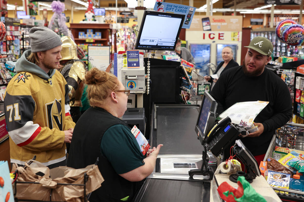 Golden Knights center William Karlsson helps customers check out at a Smith's on Monday during ...