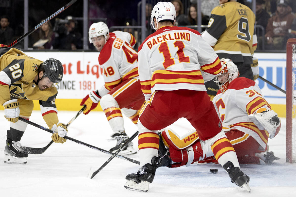 Golden Knights center Chandler Stephenson (20) slips the puck past Flames goaltender Dustin Wol ...