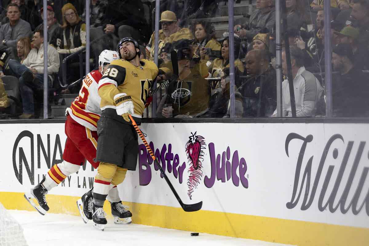 Golden Knights left wing William Carrier (28) hits the boars alongside Flames defenseman MacKen ...