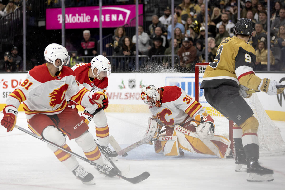 Flames goaltender Dustin Wolf (32) saves the puck after Golden Knights center Jack Eichel (9) a ...