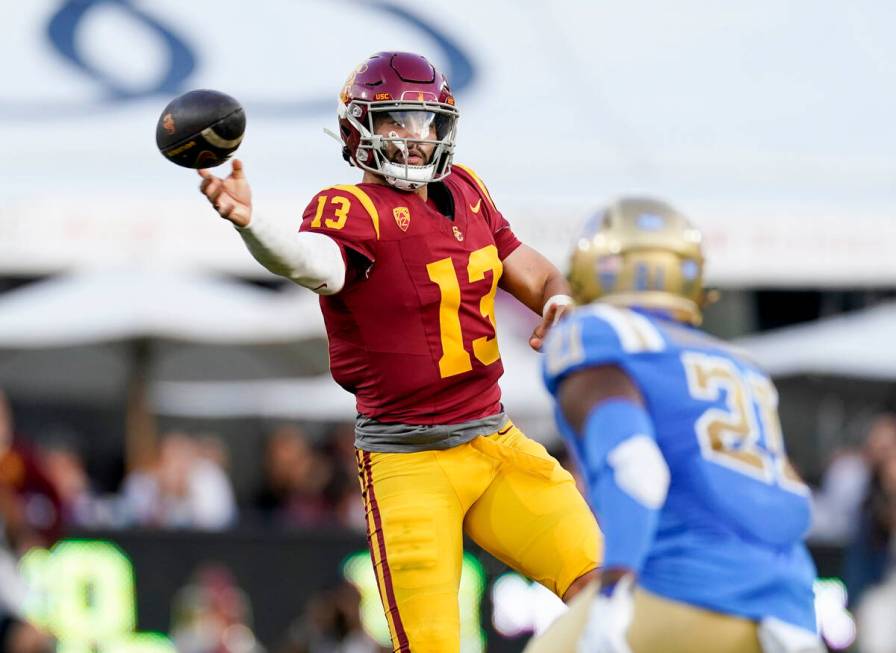 Southern California quarterback Caleb Williams, left, throws a pass as UCLA linebacker JonJon V ...