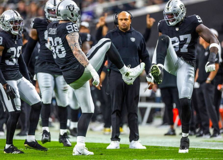 Raiders defensive end Maxx Crosby (98) and defensive end Janarius Robinson (97) share a high ki ...