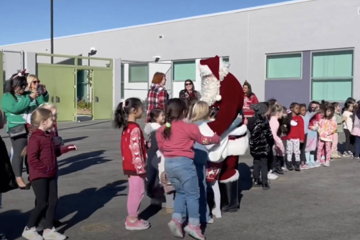 This screenshot from video shows Santa Claus distributing toys to students at Divich Elementary ...