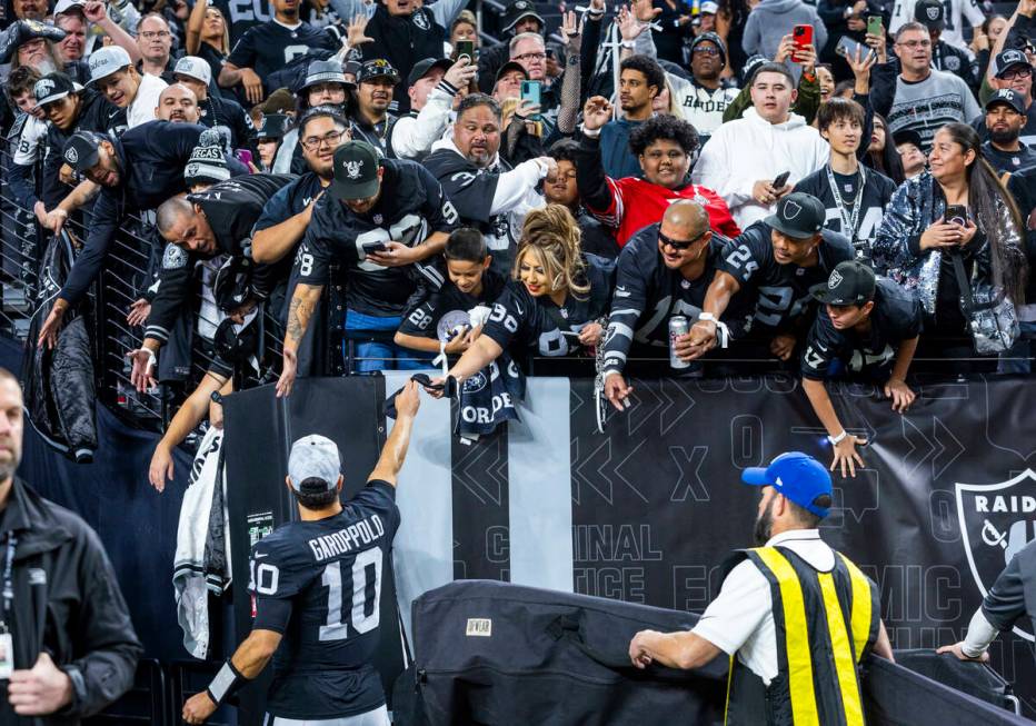 Raiders quarterback Jimmy Garoppolo (10) gives away an arm band to a fan after defeating the Lo ...