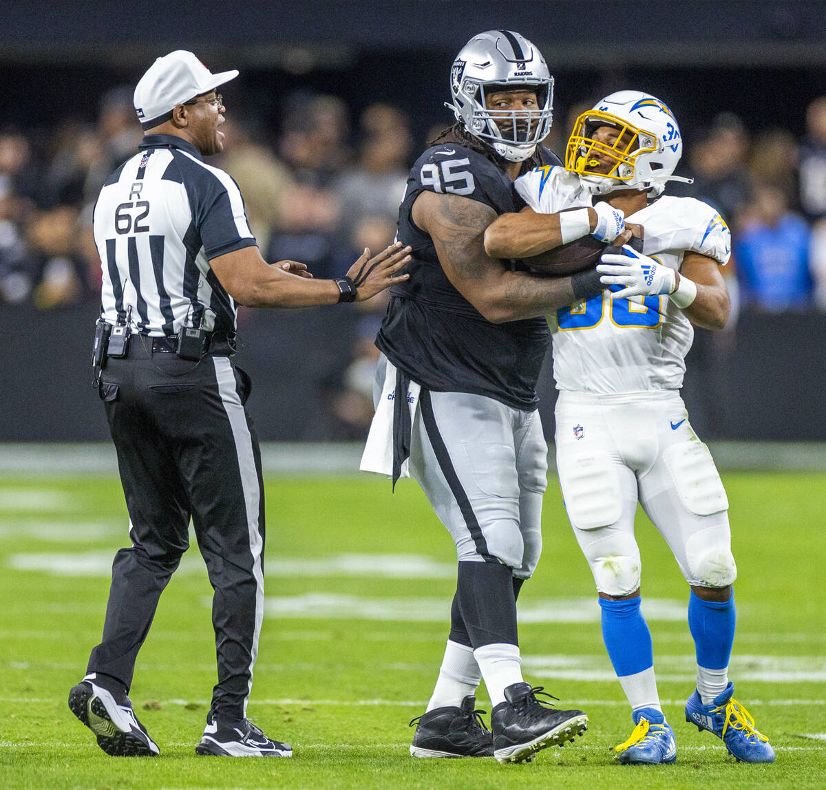 Raiders defensive tackle John Jenkins (95) wraps up Los Angeles Chargers running back Austin Ek ...