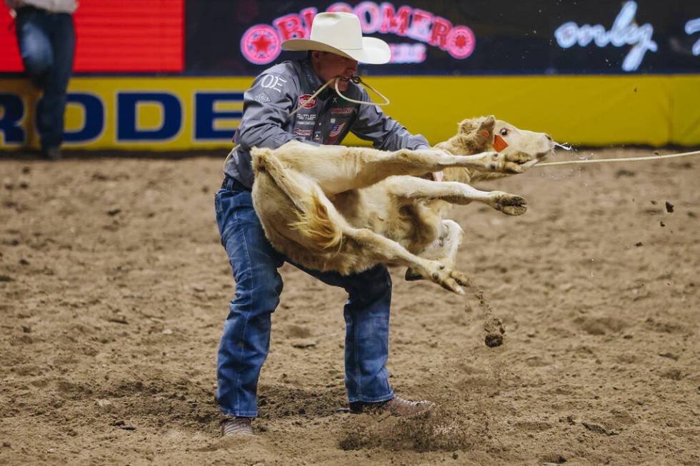 Riley Webb picks up the calf during tie down roping at the National Finals Rodeo at the Thomas ...