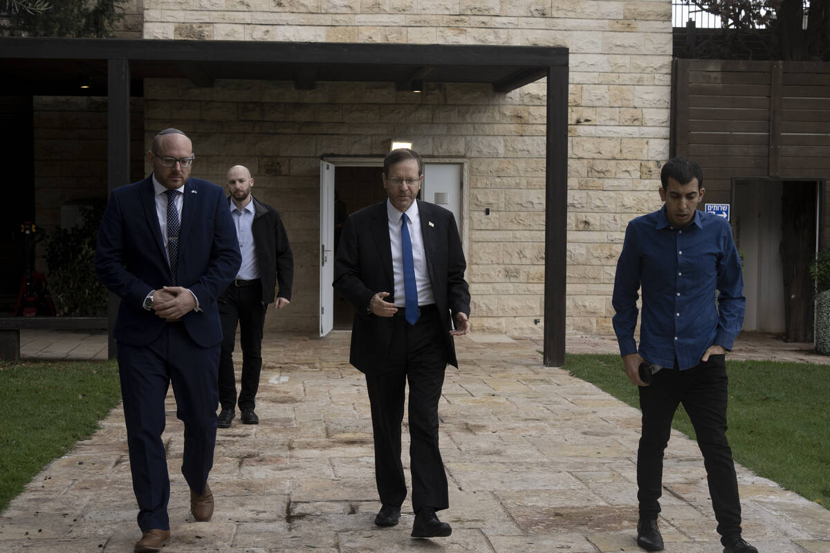 Israel's President Isaac Herzog, center, walks with his staff after an interview at his officia ...