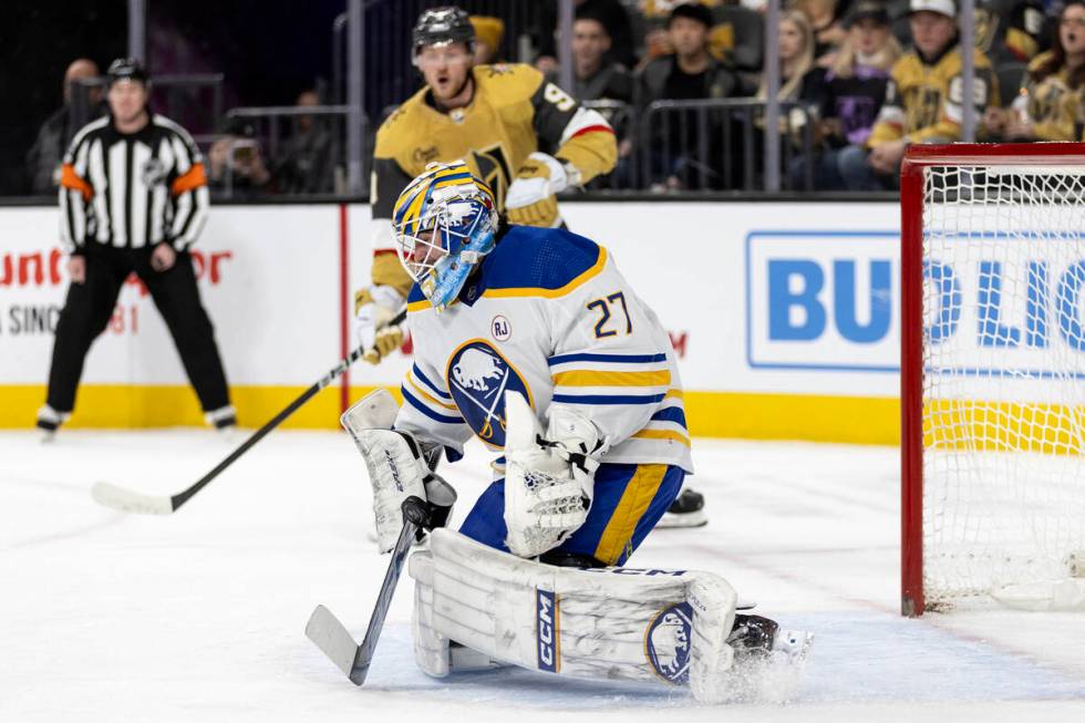 Sabres goaltender Devon Levi (27) saves the puck while Golden Knights center Jack Eichel (9) re ...