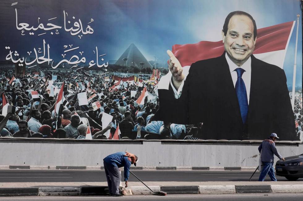 Workers clean the street under a billboard supporting Egyptian President Abdel Fattah el-Sissi ...