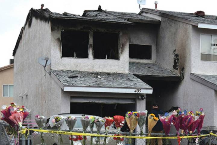 Flowers, stuffed animals and candles are placed on and along a chain-link fence in a makeshift ...