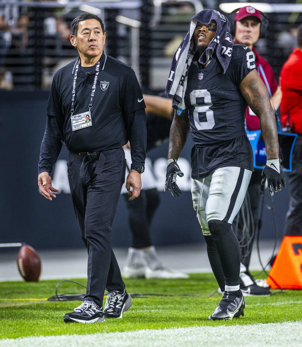 Raiders running back Josh Jacobs (8) is escorted off the filed by Dr. Michael Miao, a team orth ...