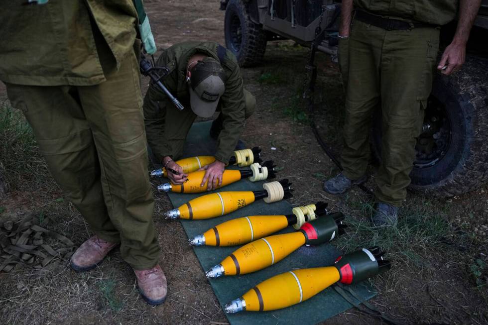 An Israeli soldier writes on a mortar in a position near the Israel-Gaza border on Wednesday, D ...