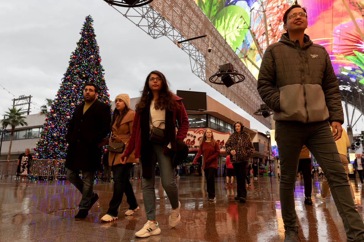 Visitors to Fremont Street Experience stroll through rainy weather on Friday, Dec. 22, 2023, in ...