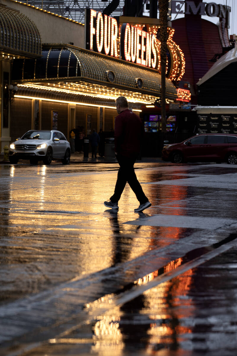 A pedestrian walks on rainy roads near Four Queens at Fremont Street Experience on Friday, Dec. ...