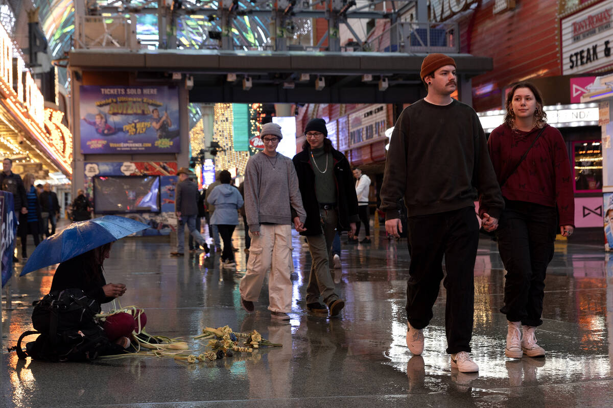 Visitors to Fremont Street Experience stroll through rainy weather on Friday, Dec. 22, 2023, in ...